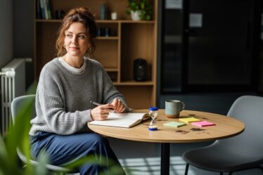 pszichológiai készségfejlesztés: nő jegyzetel otthoni műhely asztalnál, homokóra, matricák